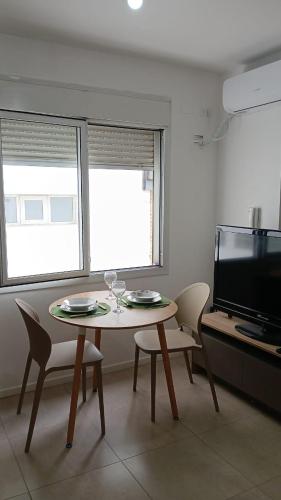 a dining room with a table and chairs and a television at Punto Sur Apart in Río Cuarto