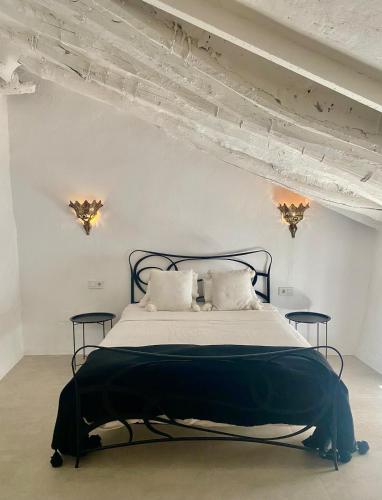 ein weißes Schlafzimmer mit einem schwarzen Bett und zwei Tischen in der Unterkunft Zarcillo in Olvera