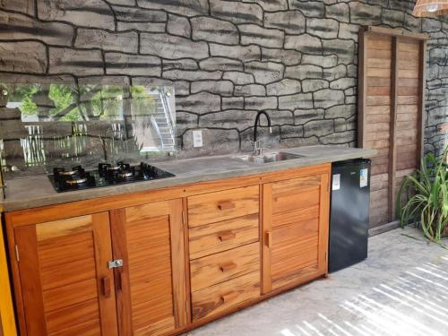 a kitchen with a sink and a stone wall at Chalé Jacuzzi Fortim in Fortim