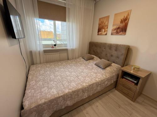 a small bedroom with a bed and a window at Smiltelė apartamentai in Varėna