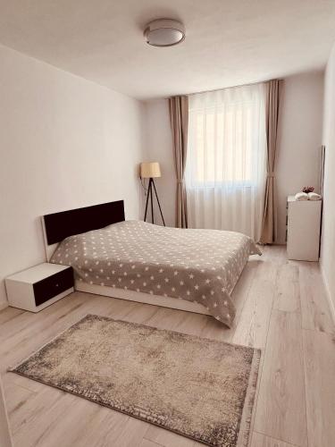 a white bedroom with a bed and a rug at City View Apartment in Mitrovica