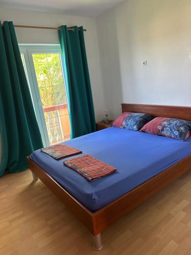 a bedroom with a bed with blue sheets and a window at Villa M, App 4 - 6 persons direct on the seaside, 1st floor in Ljubač
