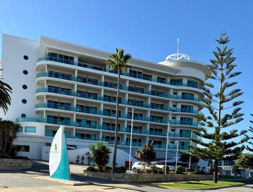a large white building with palm trees in front of it at HAVEN by the Sea in Mandurah