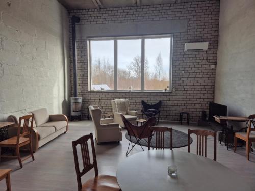 ein Wohnzimmer mit Stühlen und Tischen und einem Fenster in der Unterkunft Köima Loft in Kõima