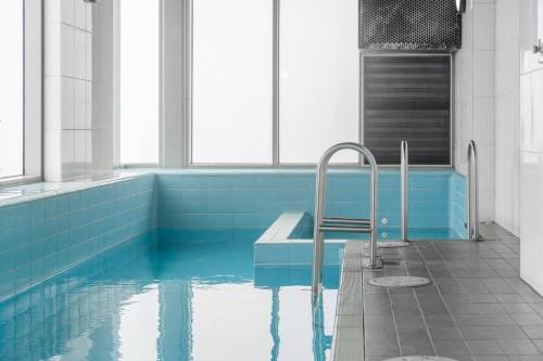 a bathroom with a tub with blue tiles at Puddings Home Compact Apartment State Library in Melbourne
