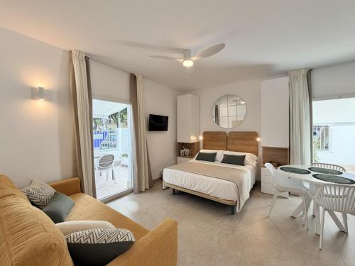 a bedroom with a bed and a couch and a table at Villa Julia Apartamentos in Chipiona