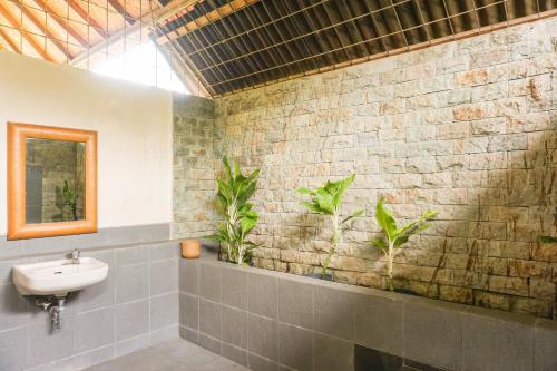 a bathroom with a sink and plants on the wall at Roemah Nelayan in Montongbuwoh