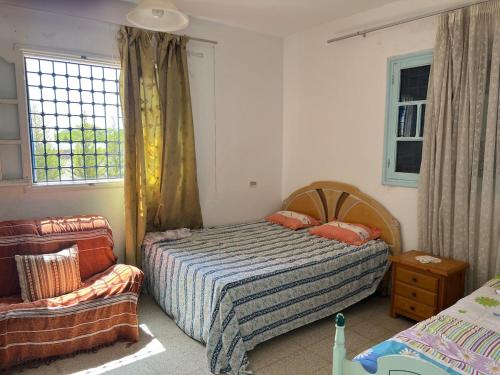 a bedroom with a bed and a chair and a window at Spacious villa for holidays in Kerkouene