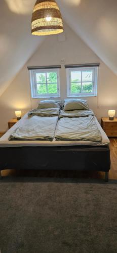 a large bed in a room with two windows at Stora Beddinge - Moon apartment in Klagstorp
