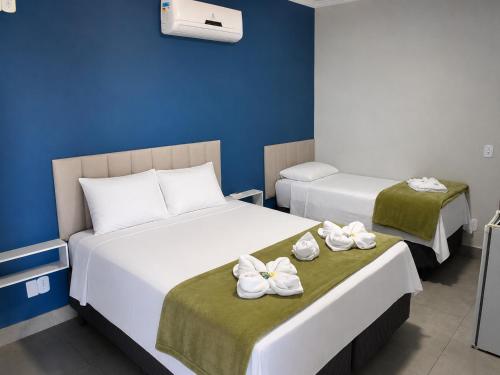 two beds in a hotel room with towels on them at Pousada Recanto das Águas - Fama MG in Fama