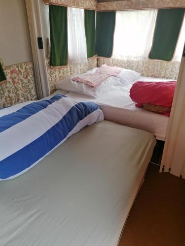 two beds sitting next to each other in a room at Caravane au bord de la rivière in Saint-Corneille