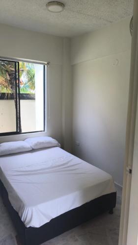 a bedroom with a white bed with a window at Villas del Oasis in Ricaurte