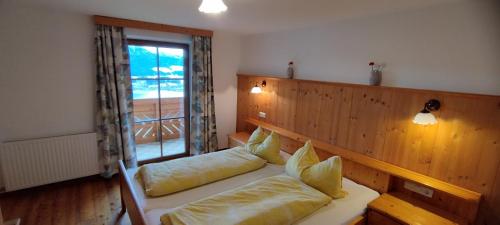a room with a bed with pillows and a window at Familienhof Kain in Tiefgraben