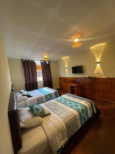 a hotel room with two beds and a flat screen tv at GoldenBird Mindo in Mindo