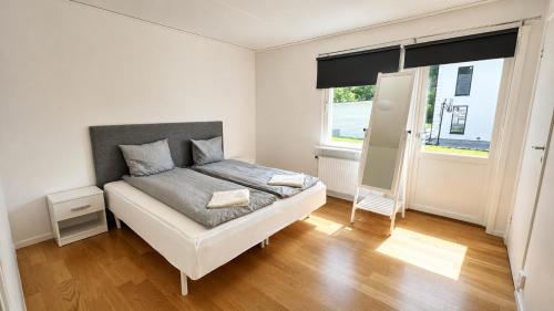 a white bedroom with a bed and a window at Villa Kaxberg in Södertälje