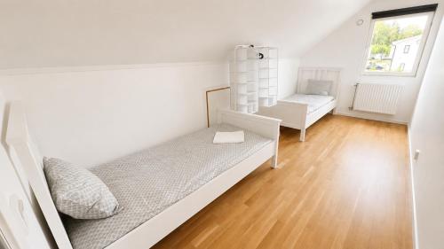 a white bedroom with a bed and a chair at Villa Kaxberg in Södertälje