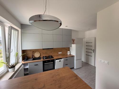 a kitchen with white appliances and a large light fixture at Apartament Modrzewia in Elblag