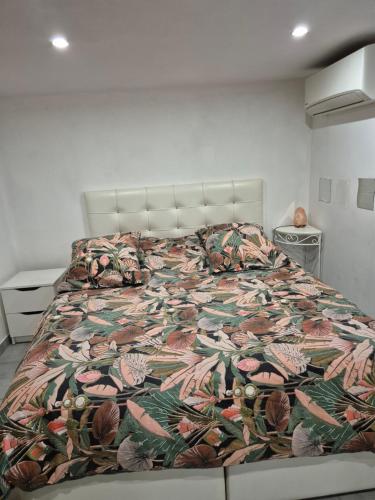 a bed with a floral comforter in a bedroom at Joli rez de jardin in La Seyne-sur-Mer