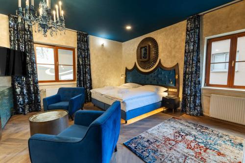 a bedroom with a bed and two blue chairs at Boutique rooms Fabrika in Děčín