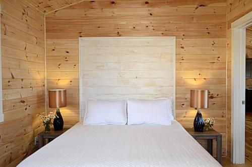 a bedroom with a white bed with two lamps at Still Point Lodge in Deep Brook
