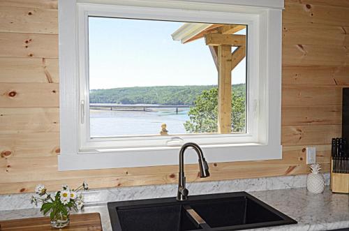 a window over a kitchen sink with a view of the water at Still Point Lodge in Deep Brook