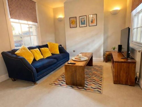 a living room with a blue couch and yellow pillows at Cosy Townhouse in Central Leamington with parking in Leamington Spa