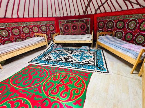 a room with two beds and a rug in a yurt at Aspan Kazakh Ger Camp in Ölgiy