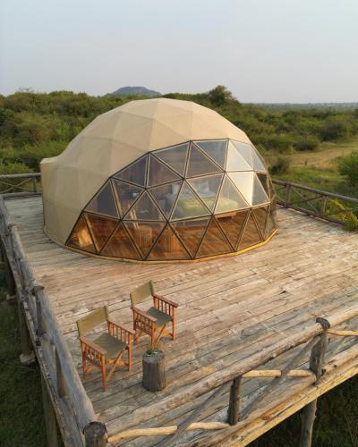 a dome tent with chairs and tables on a wooden deck at Kuoom Serengeti in Robanda