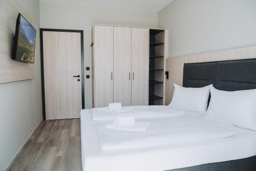 a white bedroom with a large white bed and a door at Fewo Mauterndorf in Mauterndorf