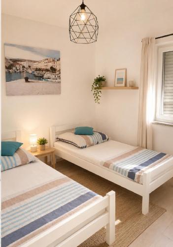 a bedroom with two beds and a window at Apartments Alma in Pag