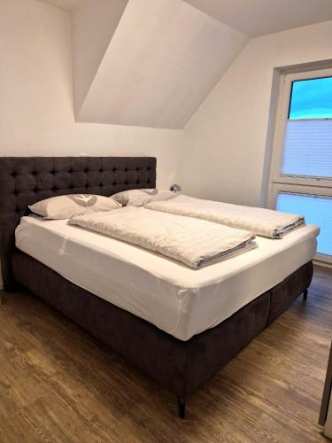 a large bed in a room with a window at Tillmanns Ankerplatz in Norden