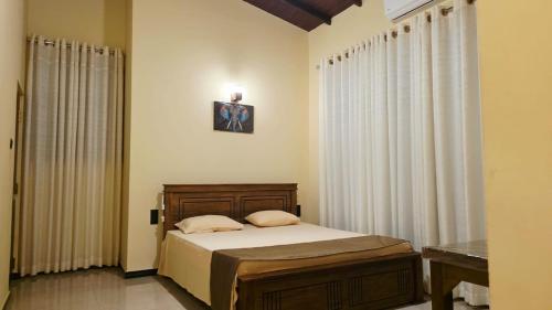 a bedroom with a bed with white walls and curtains at MARS Lodge home stay in Anuradhapura