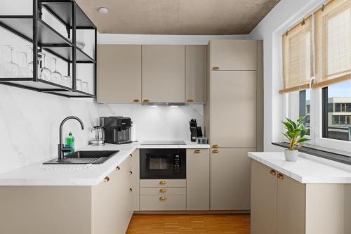 a kitchen with white cabinets and a sink at Svyvo Cologne - Serviced Apartments Ehrenfeld in Cologne