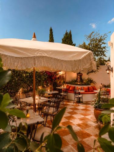 a patio with tables and chairs under a large umbrella at BV House - Membersclub - Adult only in Estepona