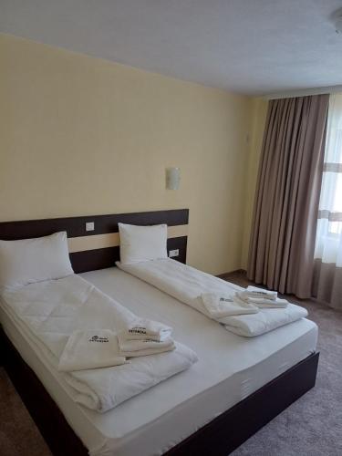 a large white bed with two white towels on it at Hotel Deyanira in Gorno Dryanovo