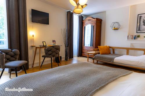 a bedroom with a bed and a table and chairs at La Maison Des Buis in Falaise