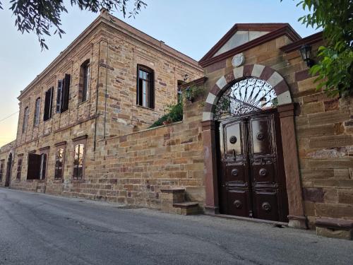 a brick building with a wooden door on a street at Arhodico Simou mansion in Kambos