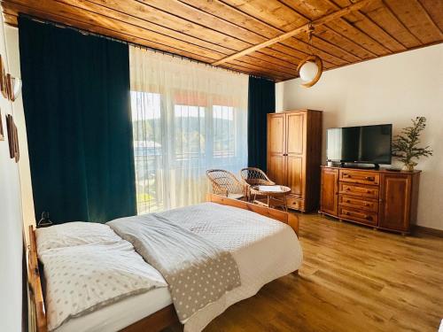 a bedroom with a bed and a flat screen tv at Wygodne Spanie in Cisna