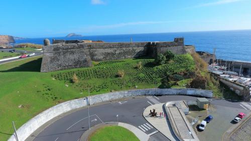 an old castle with a road next to the ocean at Pousada de Angra do Heroismo Castelo de S. Sebastiao in Angra do Heroísmo