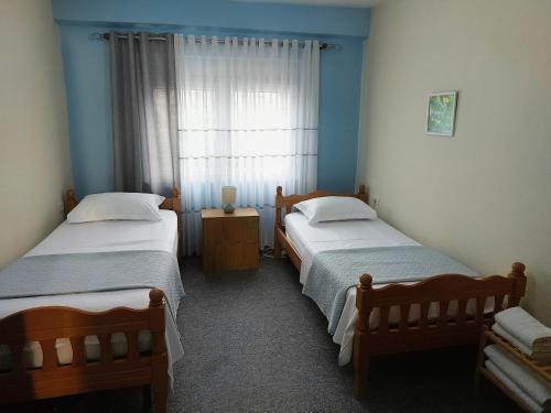 two beds in a room with blue walls and a window at Solaris Guest House in Shkodër