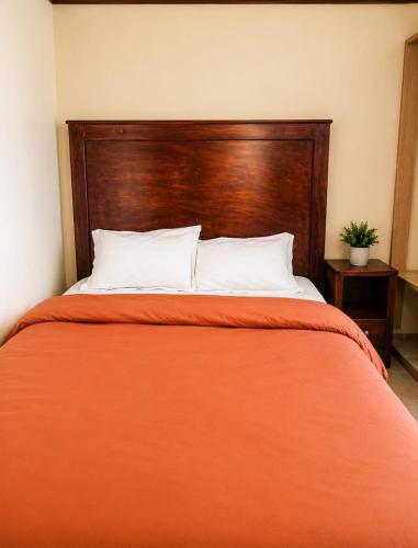 a bed with an orange blanket and a wooden headboard at Nexus Staycations in Maralal