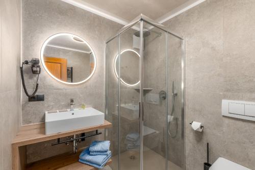 a bathroom with a sink and a shower with a mirror at Residence Diana Apartment 301 in Terento