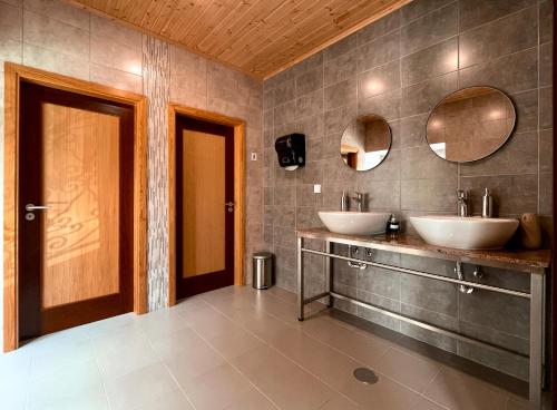 a bathroom with two sinks and two mirrors at Casa de Campo Vale do Ceira in Góis