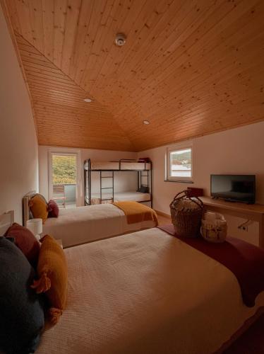 a bedroom with two beds and a flat screen tv at Casa de Campo Vale do Ceira in Góis