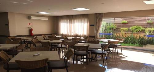 a restaurant with tables and chairs and a pool at Racini Suites Hotel in Boa Esperança