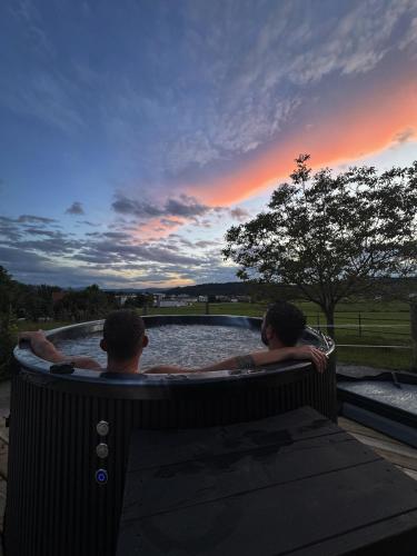 two people sitting in a hot tub in a pond at Beim Baltas in Wildpoldsried