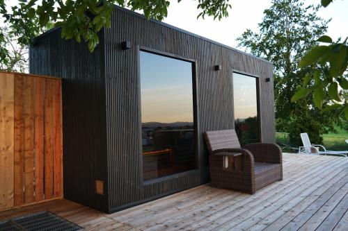 a building with glass doors and a chair on a deck at Beim Baltas in Wildpoldsried