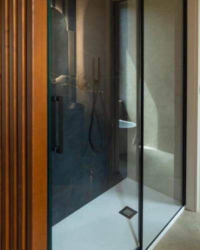 a glass shower door with a hose in a bathroom at Daga Resort in Zambrone
