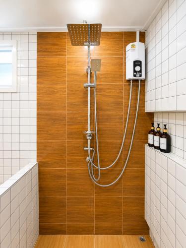 a shower in a bathroom with a wooden wall at บ้านต้นจันทร์ in Nathon Bay