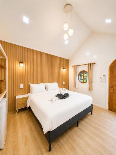 a bedroom with a large white bed with wooden walls at บ้านต้นจันทร์ in Nathon Bay